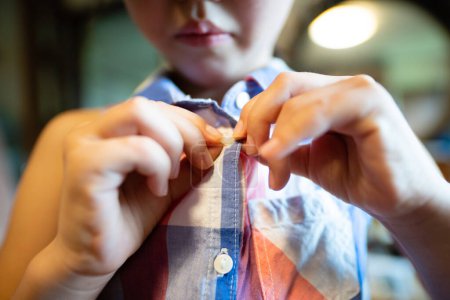 Téléchargez les photos : Bouton de fermeture mains enfant sur chemise - en image libre de droit
