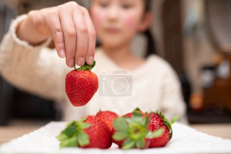Photo for Girl's hand holding a strawberry - Royalty Free Image