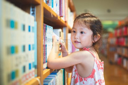 Photo for Cute girl looking at books in library - Royalty Free Image