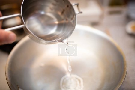 Téléchargez les photos : Verser l'eau de la tasse à mesurer dans la casserole - en image libre de droit