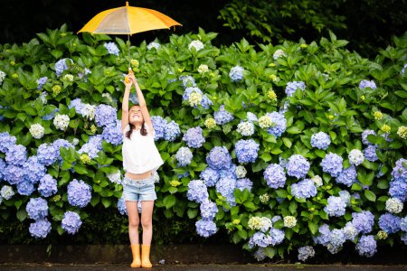 Foto de Chica con paraguas cerca de hortensias flores - Imagen libre de derechos