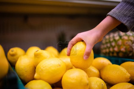 Photo for Hand of a child holding a lemon in a supermarket - Royalty Free Image