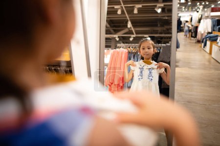 Téléchargez les photos : Fille choisir des vêtements en utilisant un miroir - en image libre de droit