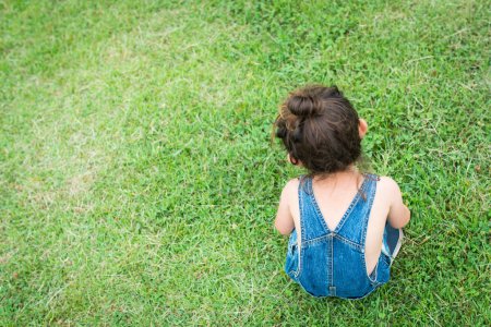 Photo for Girl playing on grass wearing overalls - Royalty Free Image