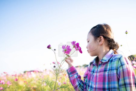 Téléchargez les photos : Fille sentir le parfum des fleurs dans le jardin de fleurs - en image libre de droit