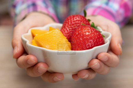 Photo for Child's hands holding a bowl of fruits - Royalty Free Image