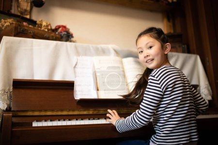 Téléchargez les photos : Fille jouer du piano à la maison - en image libre de droit
