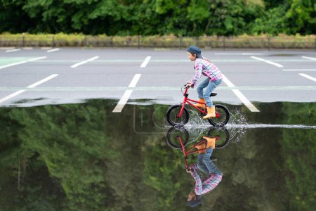 Photo for Girl riding a bicycle in a puddle - Royalty Free Image
