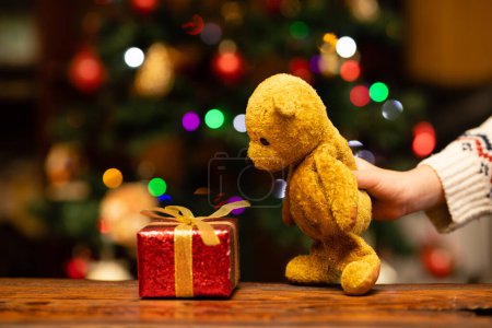 Téléchargez les photos : Les mains des enfants jouent avec le cadeau de Noël et l'ours en peluche - en image libre de droit