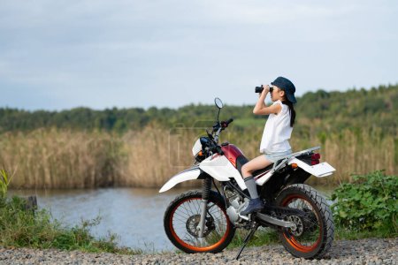 Foto de Chica montando una bicicleta todoterreno y mirando a la distancia con prismáticos - Imagen libre de derechos
