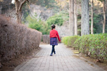 Téléchargez les photos : Vue arrière d'une fille marchant sur le trottoir - en image libre de droit
