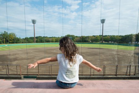 Téléchargez les photos : Fille assise dans le terrain de baseball du stand - en image libre de droit