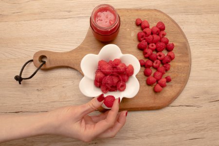 Photo for Raspberries and female hand on the table - Royalty Free Image