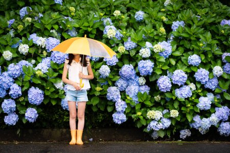 Téléchargez les photos : Fille avec parapluie près de fleurs d'hortensia - en image libre de droit