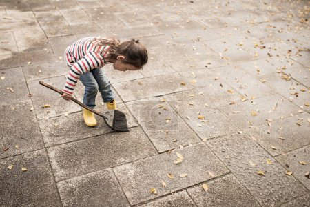 Photo for Little girl cleaning  the garden with broom - Royalty Free Image