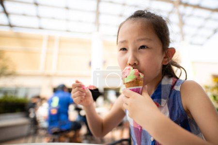 Téléchargez les photos : Fille manger de la crème glacée colorée - en image libre de droit