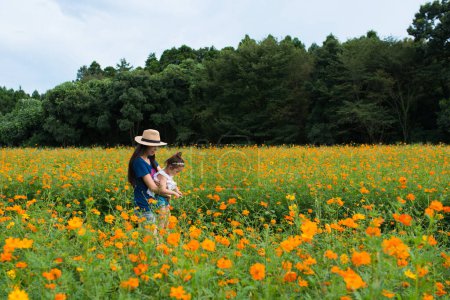 Téléchargez les photos : Mère et fille jouant dans le jardin de fleurs - en image libre de droit