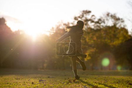 Photo for Girl playing in the park at sunset - Royalty Free Image