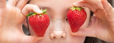 Téléchargez les photos : Fille tenant deux fraises rouges - en image libre de droit