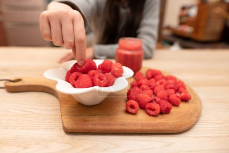 Photo for Child pinching raspberries on the table - Royalty Free Image