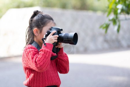 Téléchargez les photos : Une fille prenant une photo avec un appareil photo reflex mono-objectif - en image libre de droit