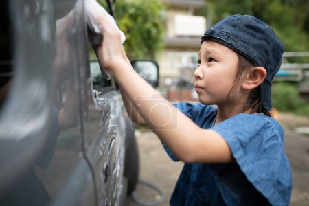Téléchargez les photos : Fille laver une voiture avec une éponge - en image libre de droit