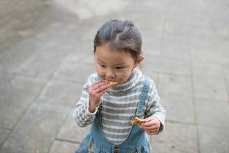 Photo for Asian child girl eating a cookie - Royalty Free Image
