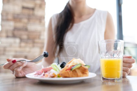 Photo for Woman eating breakfast at a restaurant - Royalty Free Image