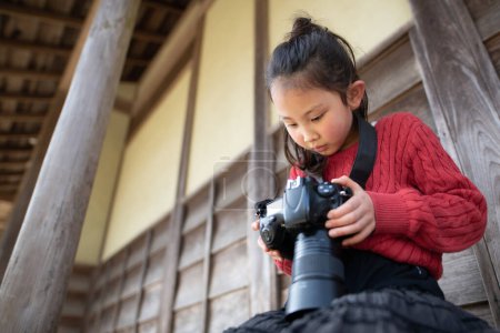 Téléchargez les photos : Une fille prenant une photo avec un appareil photo reflex mono-objectif - en image libre de droit