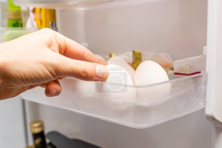 Téléchargez les photos : Main pour sortir les œufs au réfrigérateur - en image libre de droit