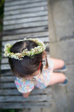 Téléchargez les photos : Fille assise sur un banc et portant une couronne de fleurs - en image libre de droit