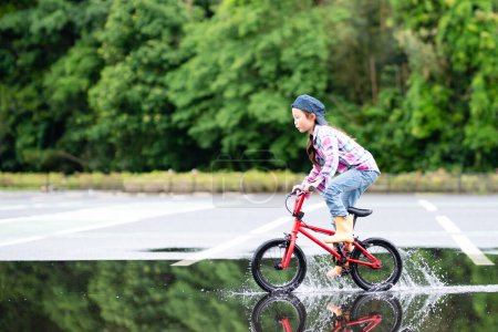 Téléchargez les photos : Fille en vélo dans une flaque - en image libre de droit