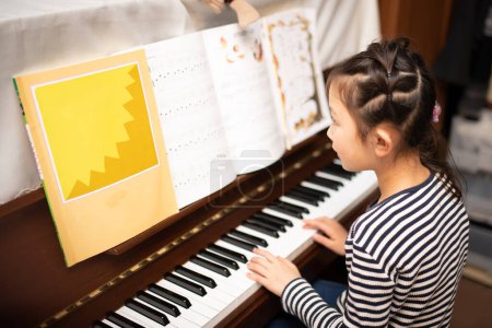 Téléchargez les photos : Fille jouer du piano à la maison - en image libre de droit