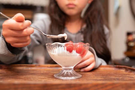 Téléchargez les photos : Un enfant qui mange du yaourt aux framboises - en image libre de droit