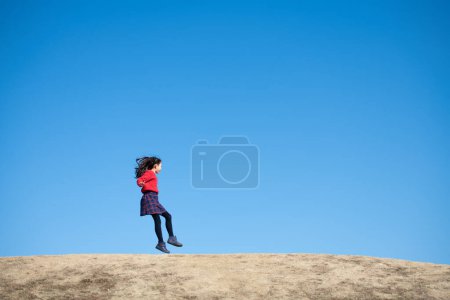 Foto de Chica saltando bajo el cielo azul - Imagen libre de derechos