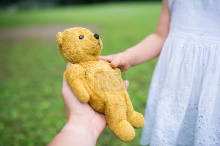 Téléchargez les photos : Mère et fille mains avec l'ours en peluche - en image libre de droit