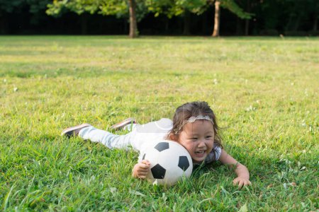Téléchargez les photos : Fille jouer avec ballon sur pelouse - en image libre de droit