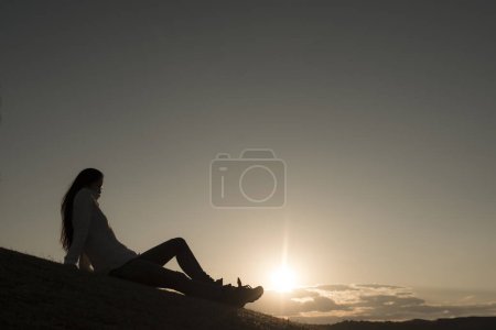 Téléchargez les photos : Silhouette de fille sur une colline au coucher du soleil - en image libre de droit