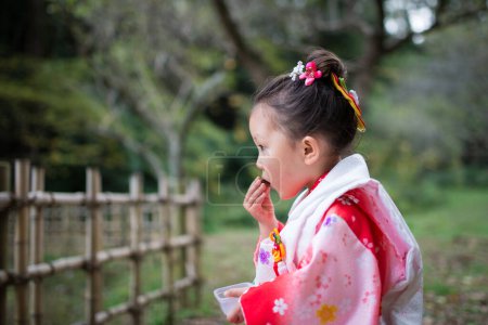 Mädchen isst einen Imbiss im Kimono