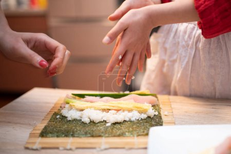 Téléchargez les photos : Parent et enfant faisant des rouleaux de sushi - en image libre de droit