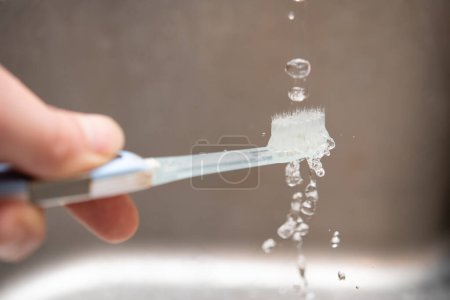 Foto de Lavar el cepillo de dientes con agua - Imagen libre de derechos