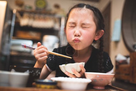 Photo for Beautiful little asian girl  eating with chopsticks - Royalty Free Image