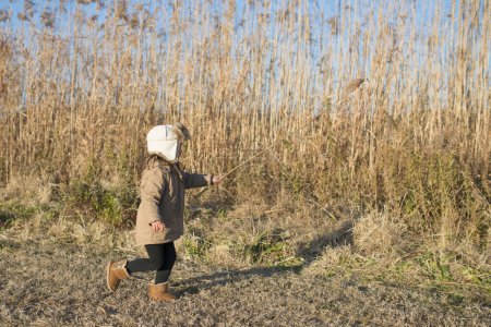 Téléchargez les photos : Fille marche sur un champ avec des plantes séchées - en image libre de droit