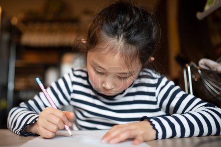 Téléchargez les photos : Fille écriture faire des devoirs à la maison - en image libre de droit