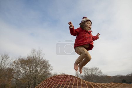 Téléchargez les photos : Mignonne petite fille asiatique jouer sur aire de jeux en hiver - en image libre de droit