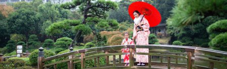 Téléchargez les photos : Femme avec parapluie et enfant portent des vêtements traditionnels dans le parc - en image libre de droit