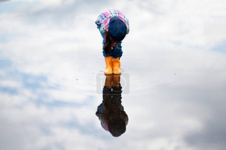 Téléchargez les photos : Enfant jouant dans une flaque - en image libre de droit