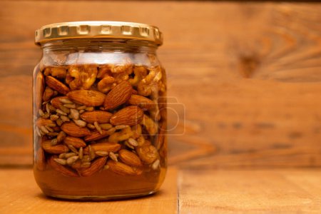 Photo for Glass jar with nuts on wooden table - Royalty Free Image