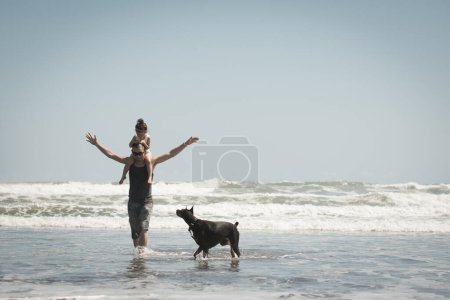 Photo for Father and daughter and dog playing on the beach - Royalty Free Image