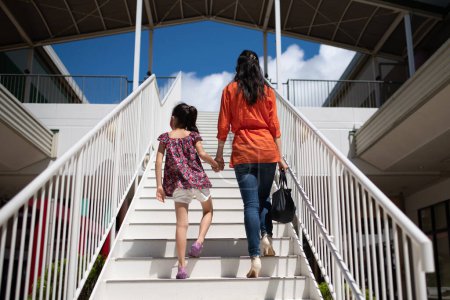 Foto de Madre e hija cogidas de la mano y subiendo escaleras - Imagen libre de derechos